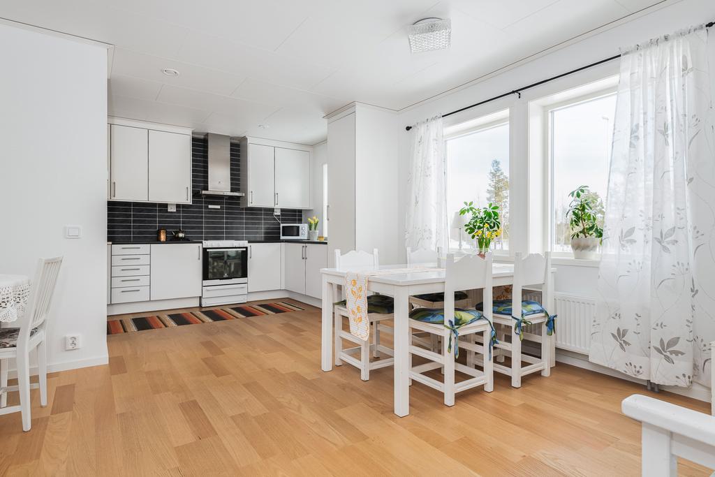 Rymligt kök med parkettgolv, tapeter på väggarna, spishäll (induktion), spisfläkt, kyl, frys, diskmaskin (oanvänd) och plats för matgrupp.
