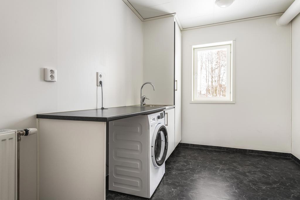 Tvättstuga med våtrumsmatta på golv och väggar, tvättmaskin och tvättho.