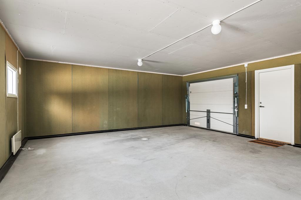 Enkelgarage med avlopp, enkelport med en dörr intill.