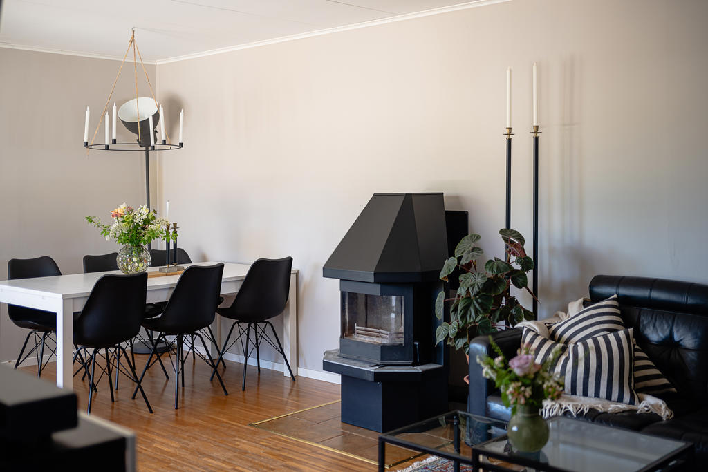 Ljust vardagsrum med både matplats, plats för soffgrupp och braskamin