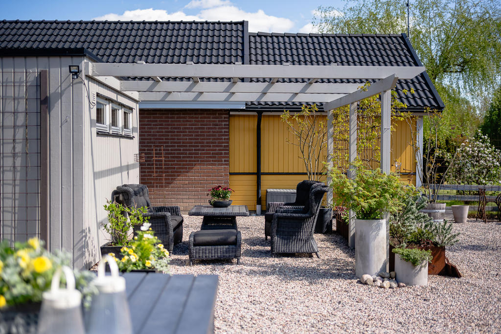 Pergola invid garagets förråd, här ger ett praktiskt solsegel skugga under sommarens varma dagar