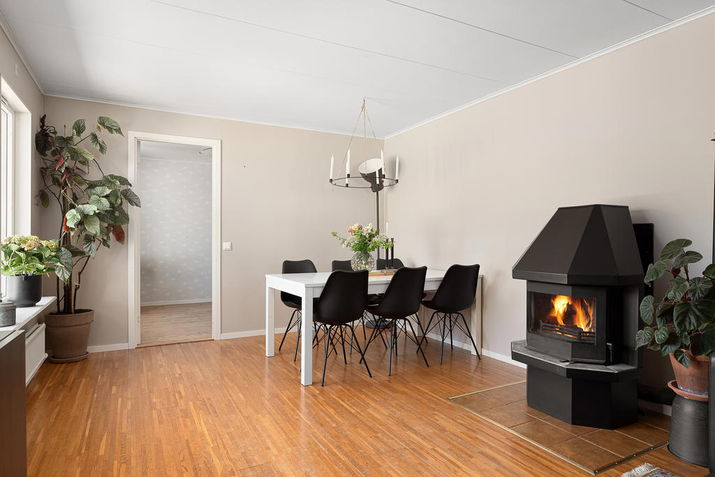 Ljust vardagsrum med både matplats, braskamin och plats för soffgrupp 