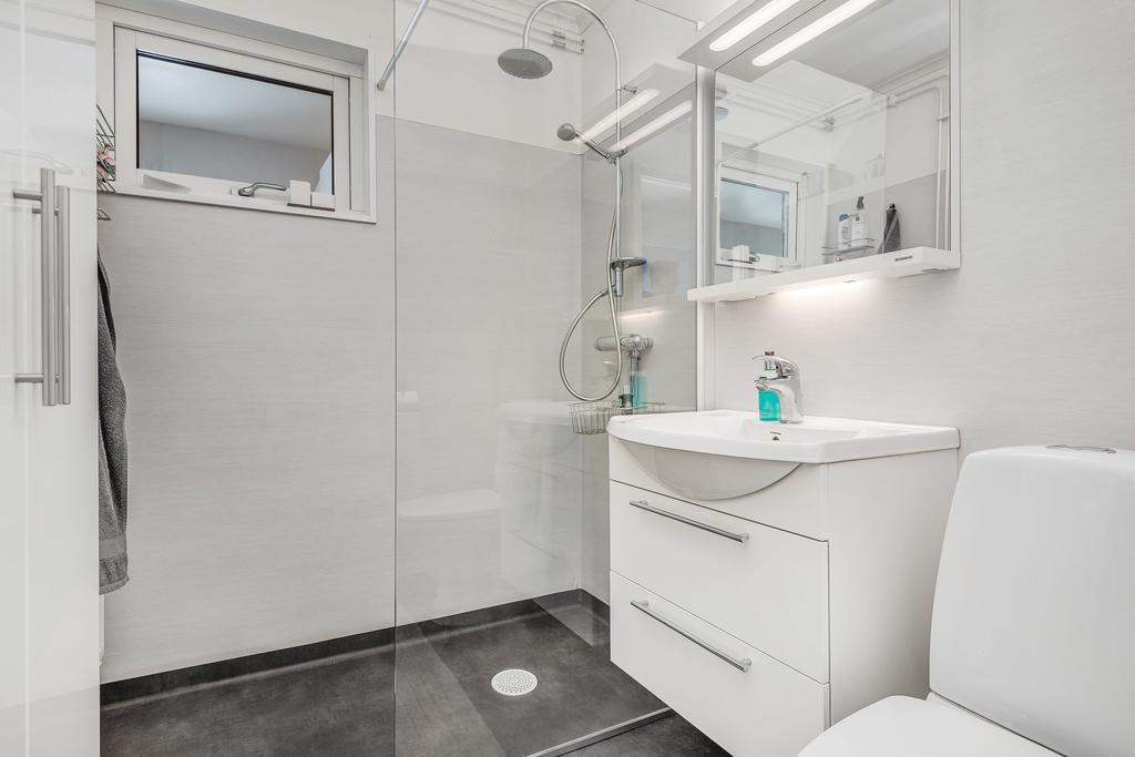 Renoverat badrum med våtrumsmatta på golv och väggar. Utrustad med wc, dusch, tvättställ och element.