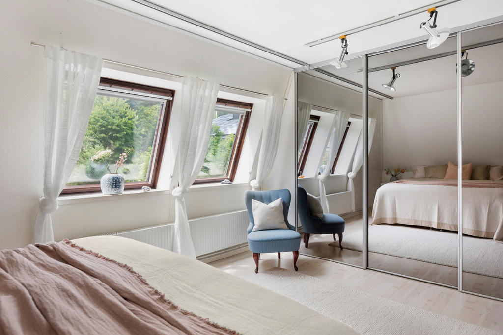 Masterbedroom med härligt ljusinsläpp och skjutdörrsgarderob med spegeldörrar och Elfa inredning.