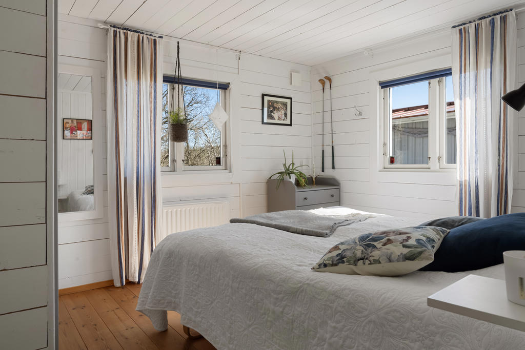 Master bedroom med plats för dubbelsäng och två fönster för ljusinsläpp.