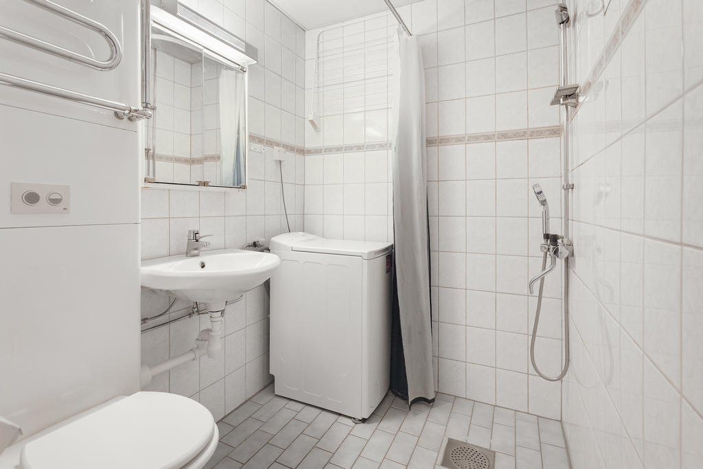 Badrummet är fräscht i kakel och klinker. Här finns en tvättmaskin för att underlätta vardagen. 