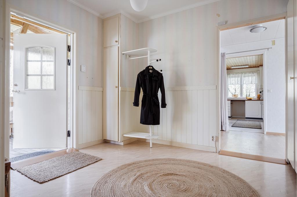 Hallen är ljus och rymlig med bra avhängningsmöjligheter och många garderober. Plastmatta på golvet och vit bröstpanel och tapet på väggarna.