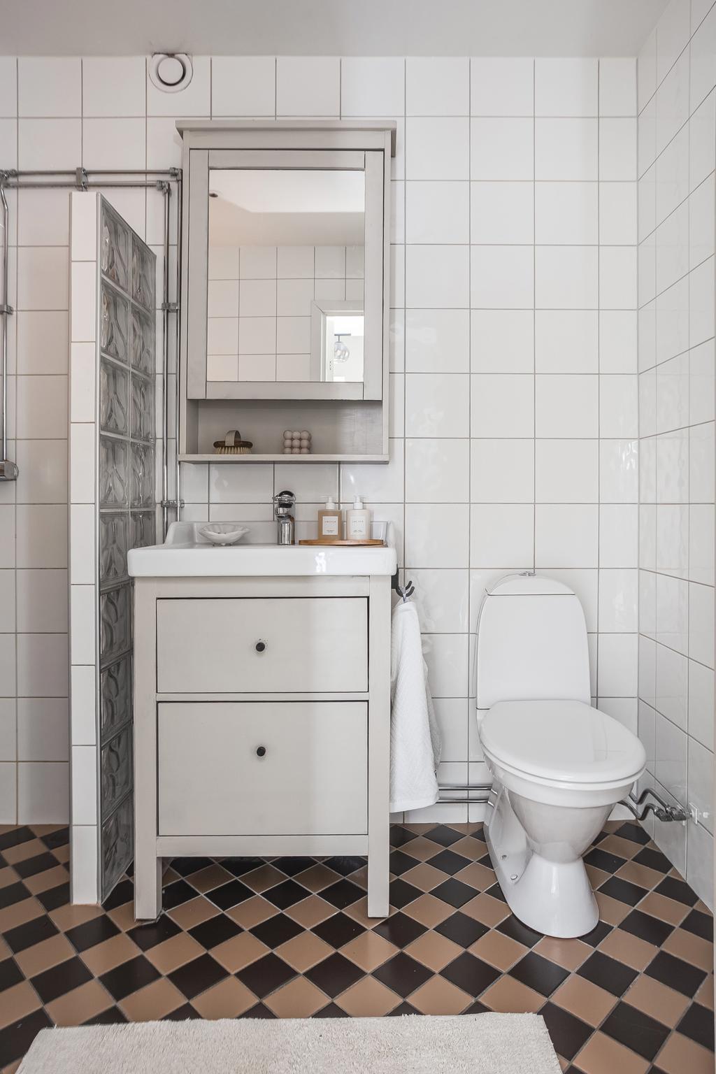 Det helkaklade badrummet följer lägenhetens tema med det tidlösa och snygga golvet 