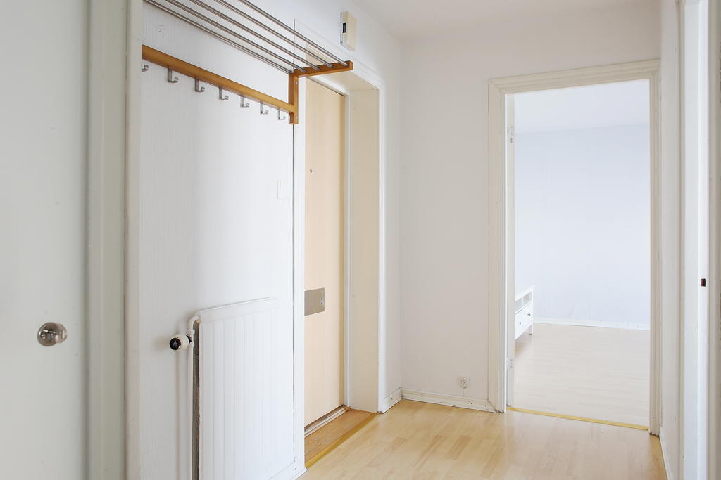 Ingång till hall med klädavhängning på hatthylla, vy mot vardagsrummet