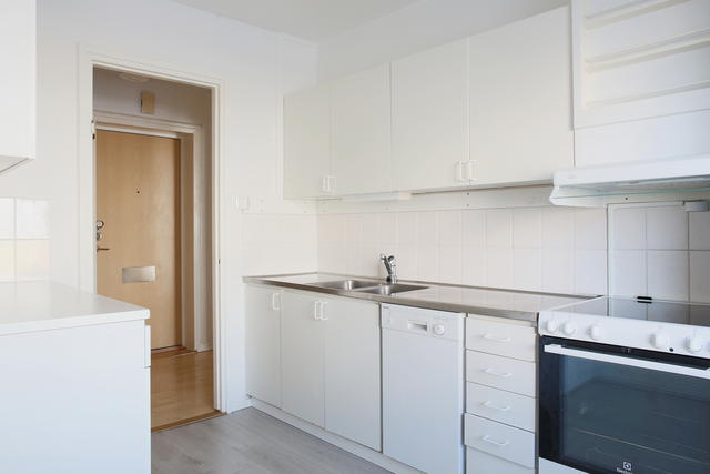 Ljust kök med rostfri diskbänk och kakel ovanför arbetsytorna 