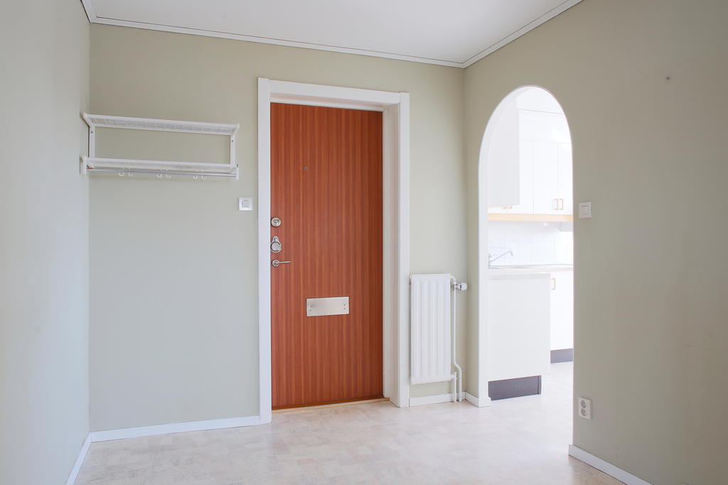 Ingång till en ljus hall som blir en knutpunkt mellan rummen i lägenheten 