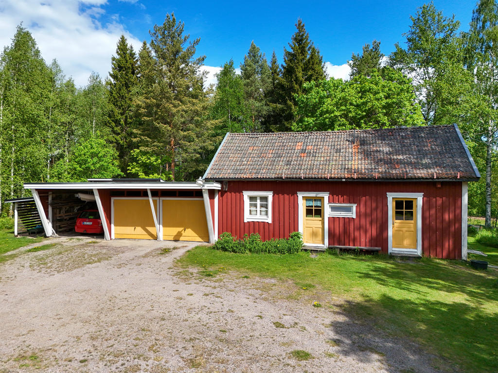 Uthus med sommarrum och förråd samt vidbyggt dubbelgarage och carport med grusgolv. 