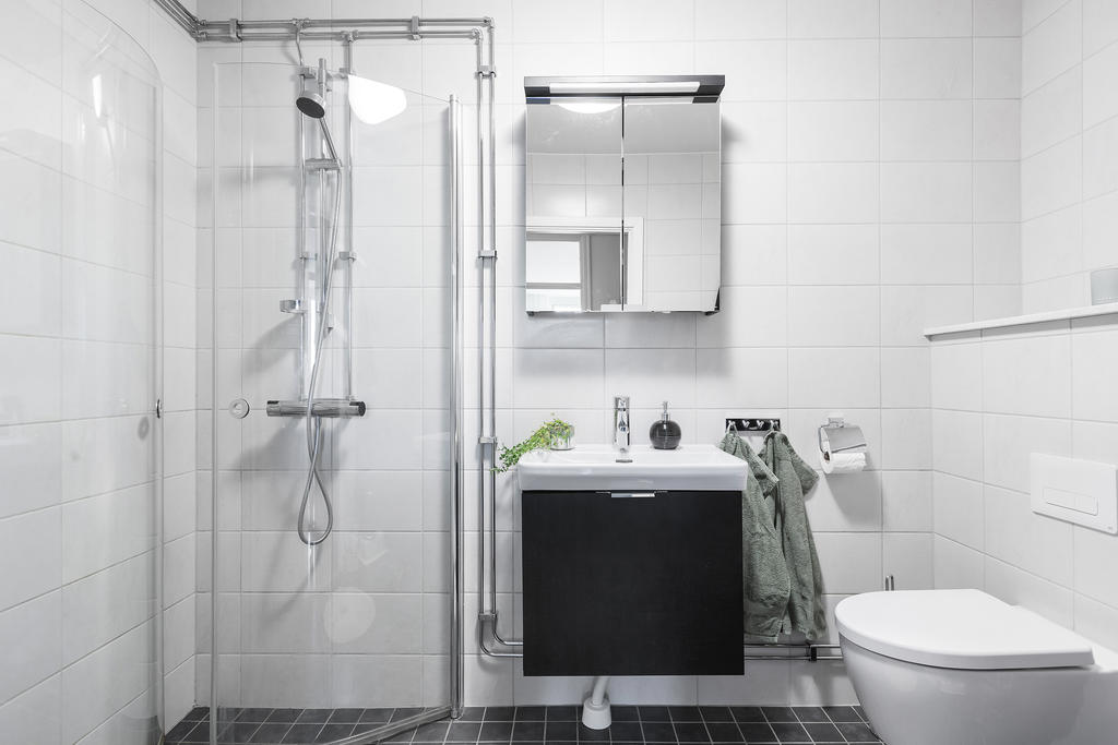 Rymligt badrum med helkaklade väggar i tidlös design.