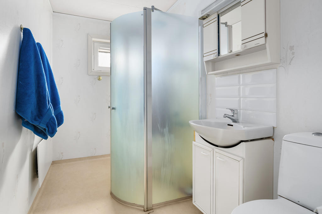 Badrum med dusch, handfat i kommod och WC