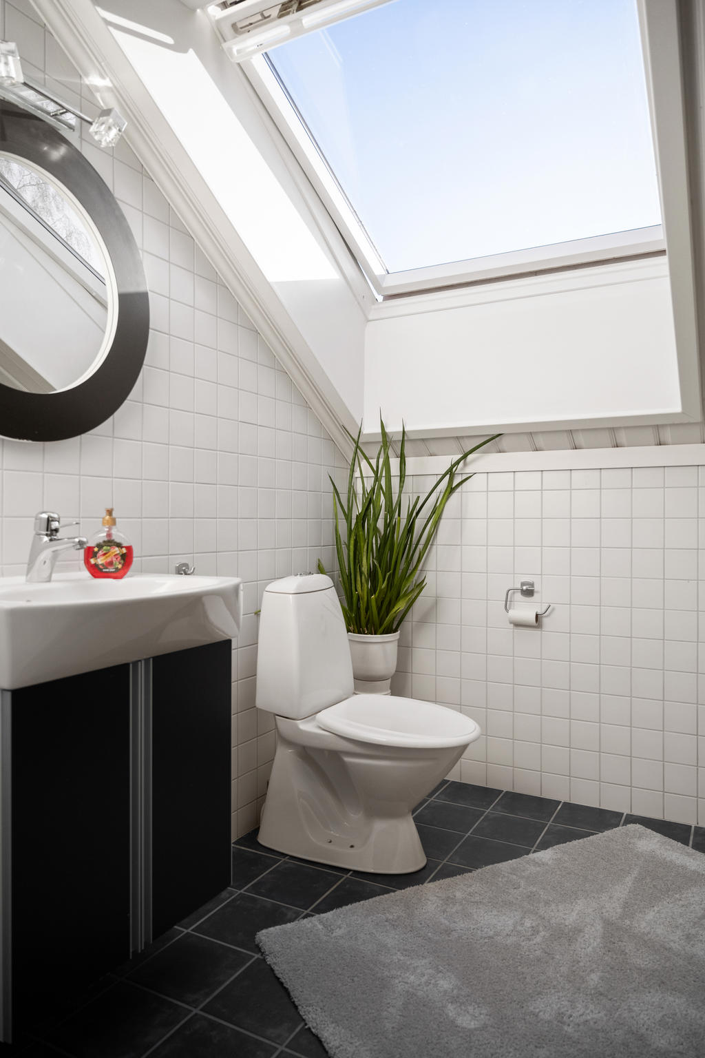 Helkaklat badrum på övre plan med duschhörna, handfat med kommod med skåp och wc.