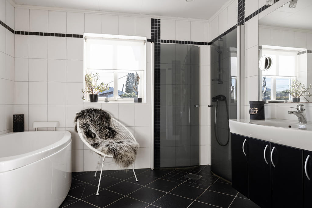 Helkaklat badrum med duschörna, snyggt badkar och kommod med bra förvaring och wc.