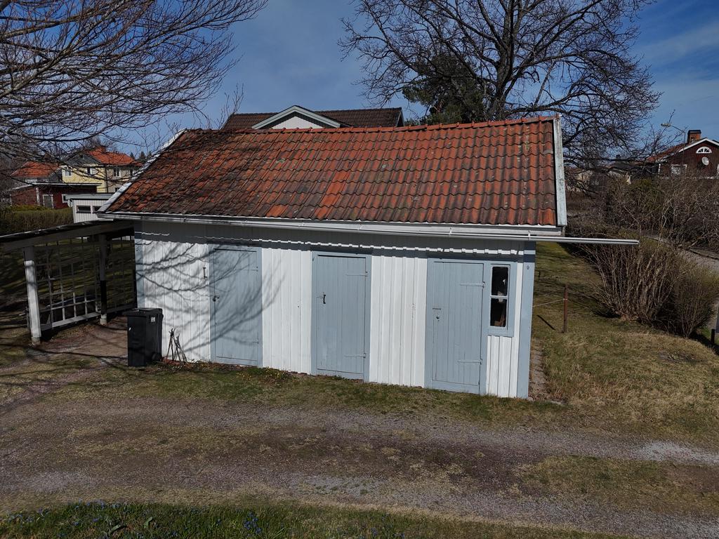 Förrådsbyggnad med carport längs kortsida.