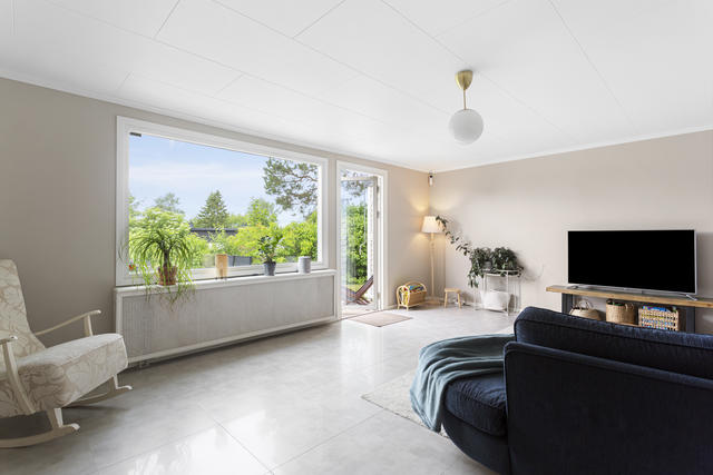 Vardagsrummet har panoramafönster och utgång till baksidans uteplats och tomten