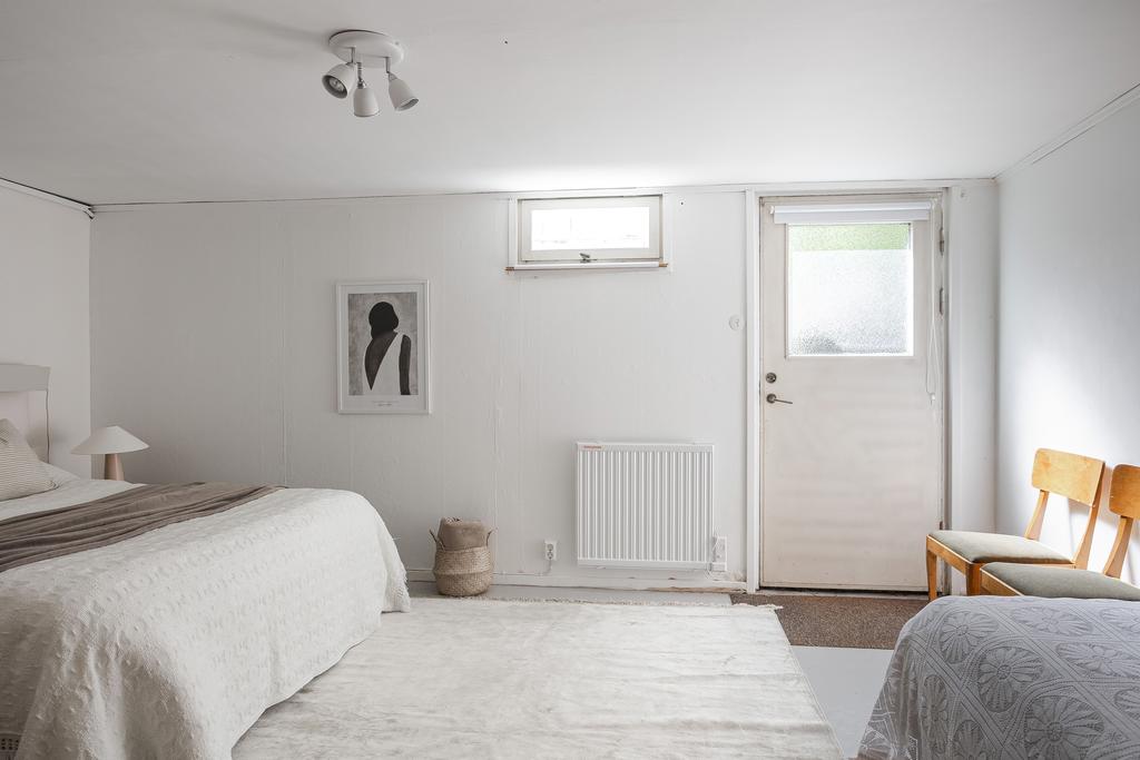 Rymligt gästrum med dörr ut mot trädgården på baksidan