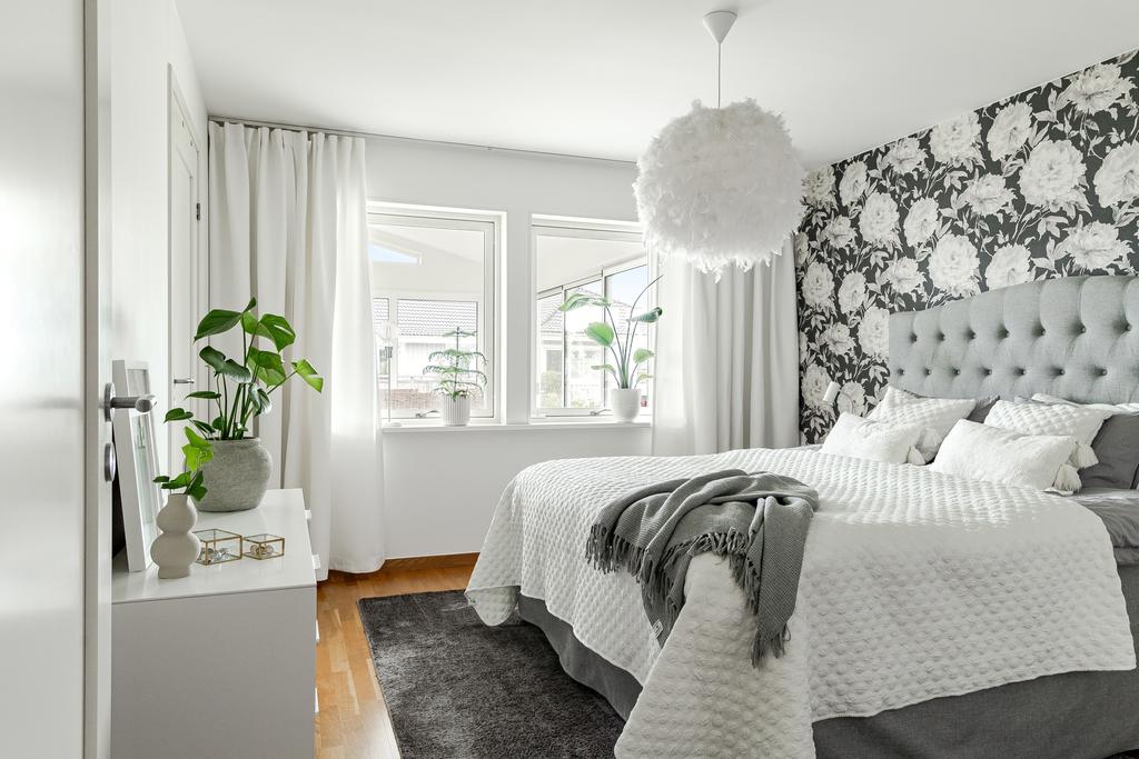 Harmoniskt sovrum med tapet i lugna toner och fint ljus. Walk-in-closet finns i anslutning till sovrummet
