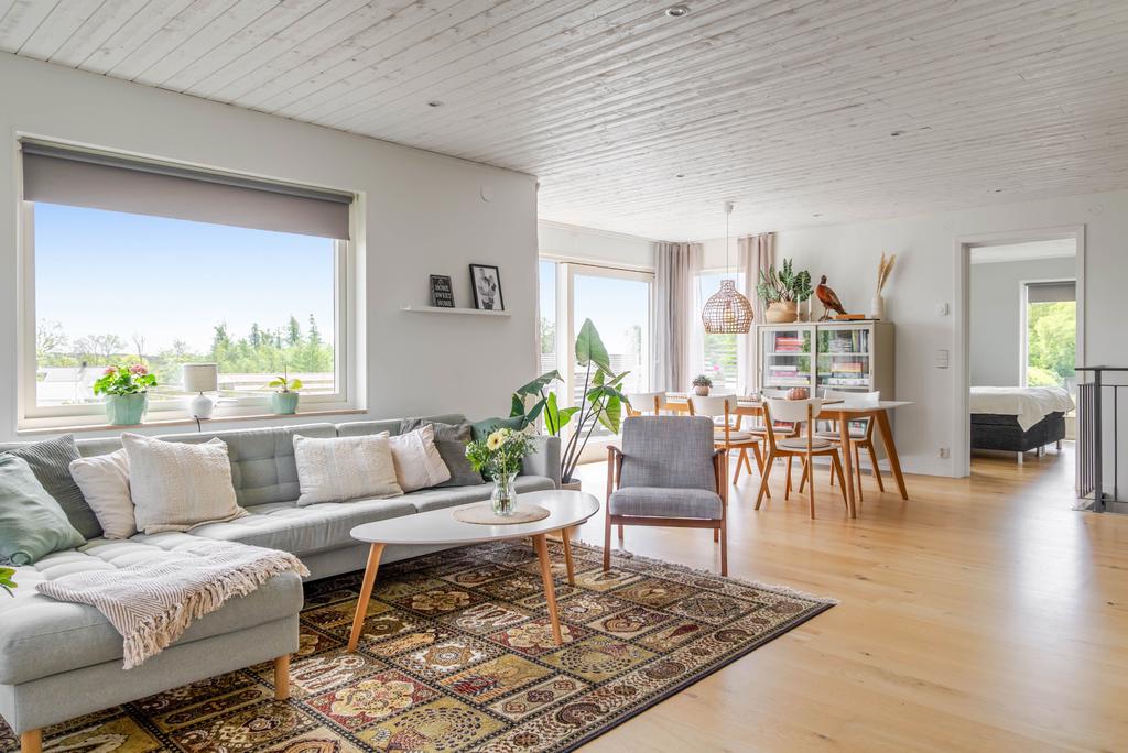 Öppen och ljus planlösning där vardagsrum, matplats och kök samspelar fint. Flera fönster och utgång till altan ger rummet ett luftigt och inbjudande intryck.