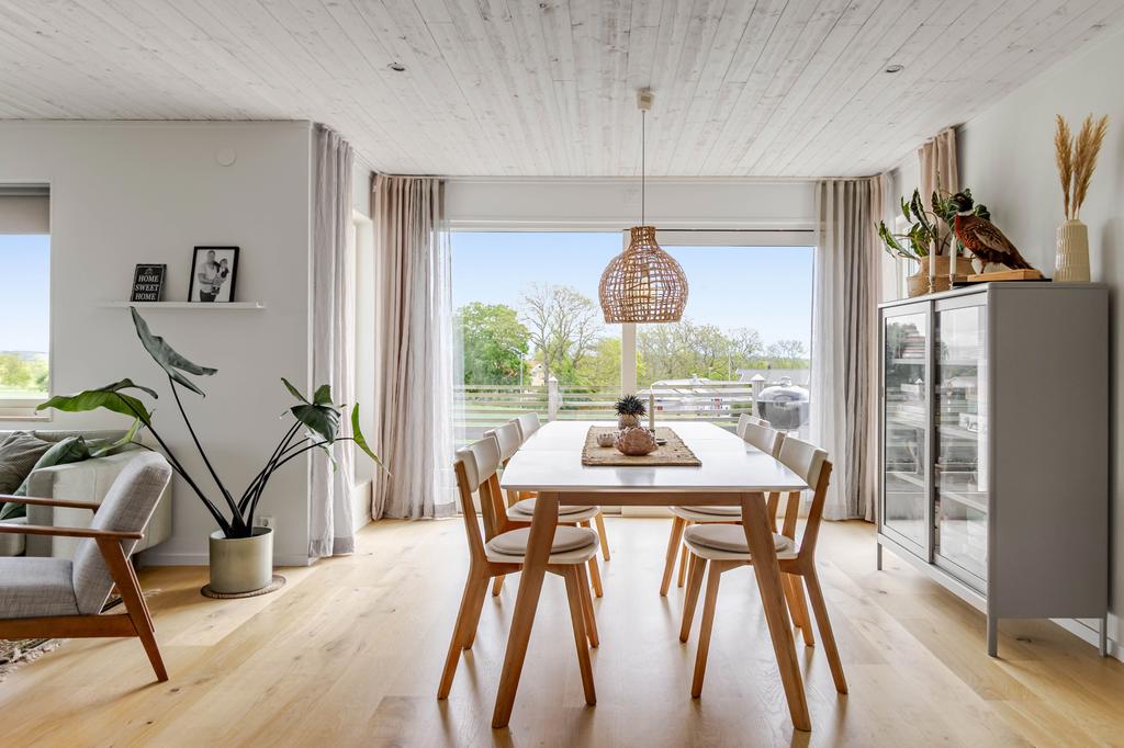 Ljus matplats med stora fönster och utgång till altanen. Här ryms det stora matbordet – perfekt för både vardagsmiddag och festligare tillfällen.
