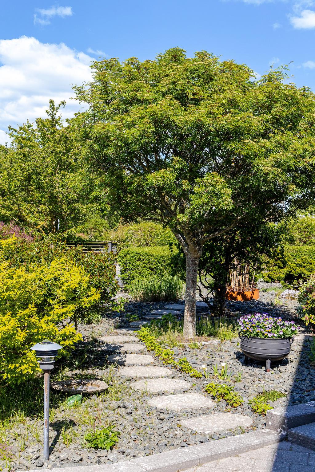 Trädgården är smakfullt anlagd med dekorativa stensättningar och blommande inslag som förhöjer helhetskänslan