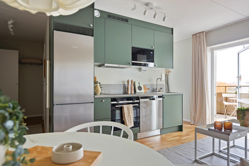 Läckert kök i en grågrön nyans och med rostfria vitvaror.