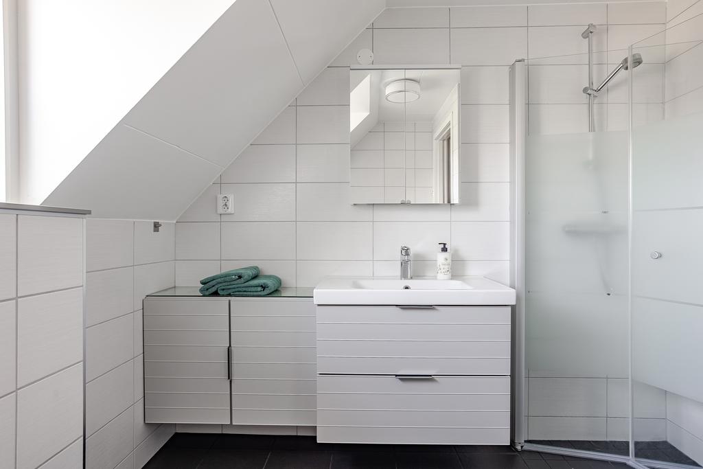 Badrum på övre plan med dusch, kommod och kaklade väggar