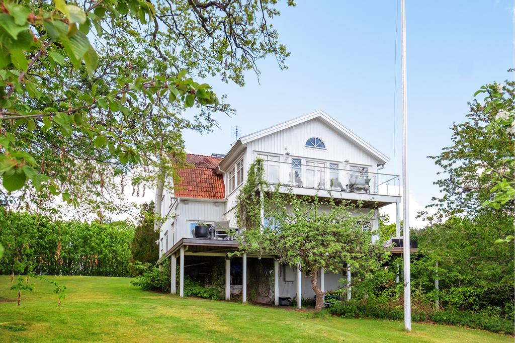 Vackert hus med spröjsade fönster, inbäddat på en lummig härlig trädgård.