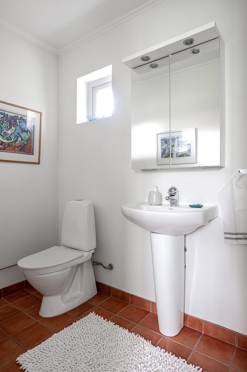 Praktisk gästtoalett med wc, tvättställ och spegelskåp.
