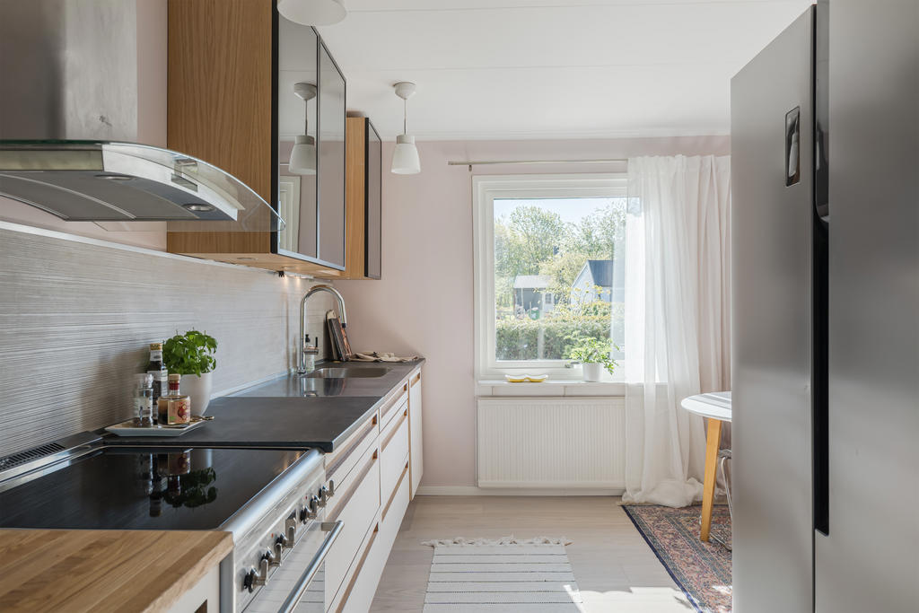 Nyinstallerat kök med med plats för matbord och stolar. Enstavs-parkett, målade väggar och kakel ovan arbetsyta.