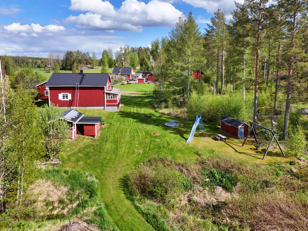 Tomt och fasad i väster. Här finns bl.a en äldre lekplats med gungor, rutchkana och en snurrkarusell. 