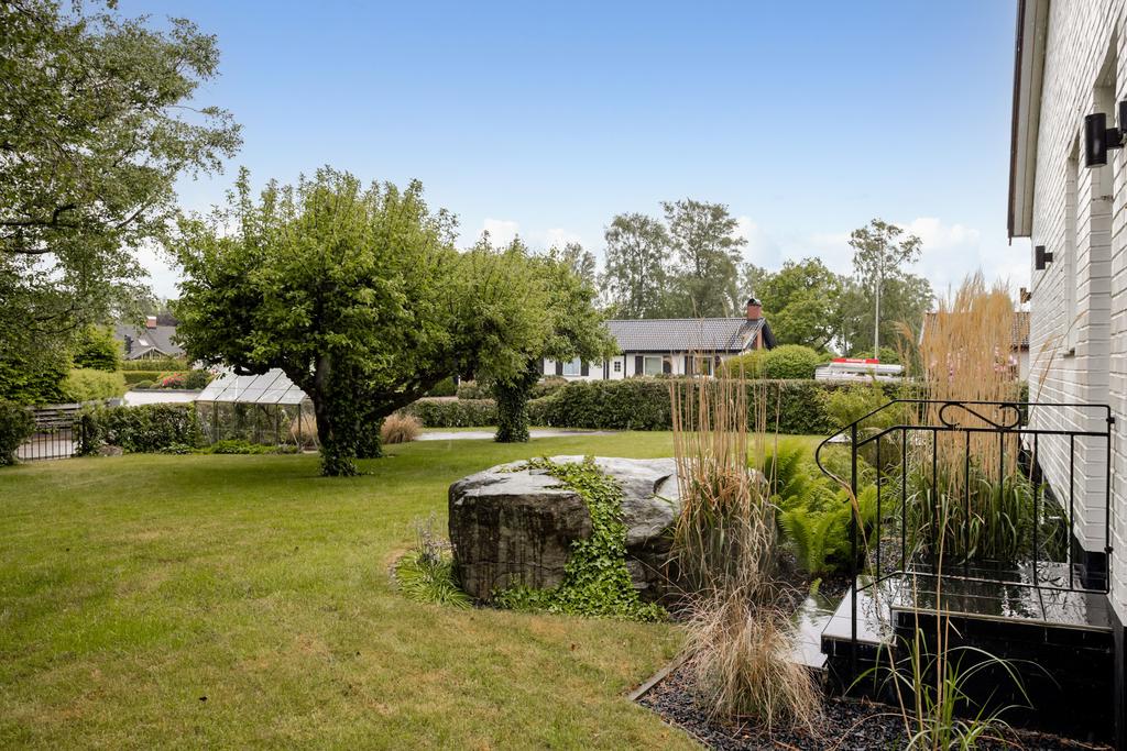 En mysig trädgård med stor gräsmatta, uteplatser och fruktträd 