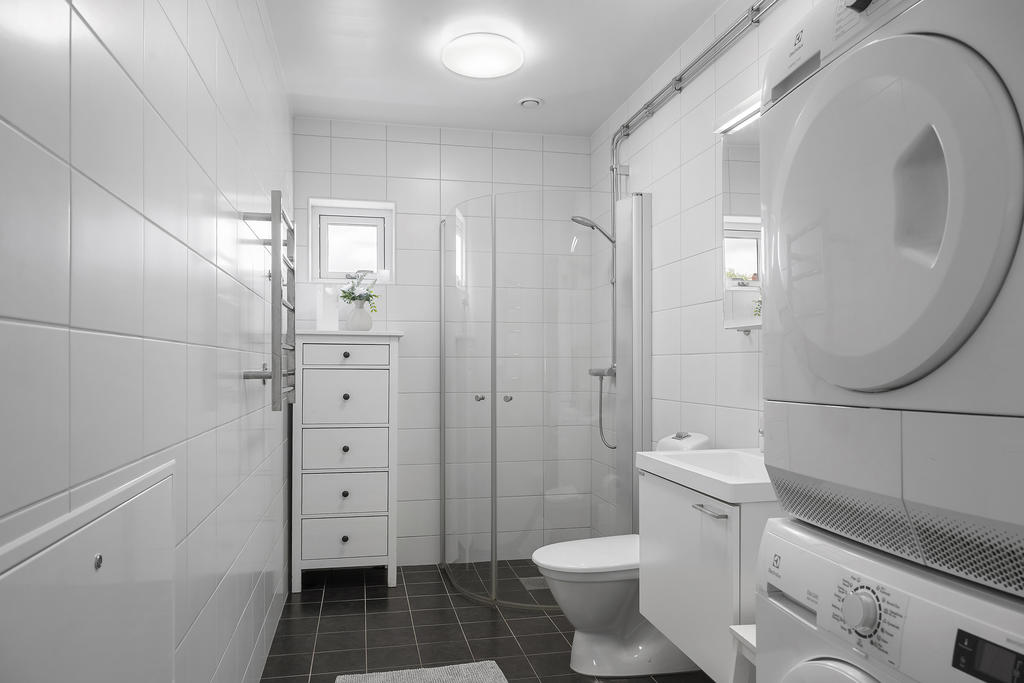 Ljust och fräscht badrum med egen tvättmaskin och torktumlare.