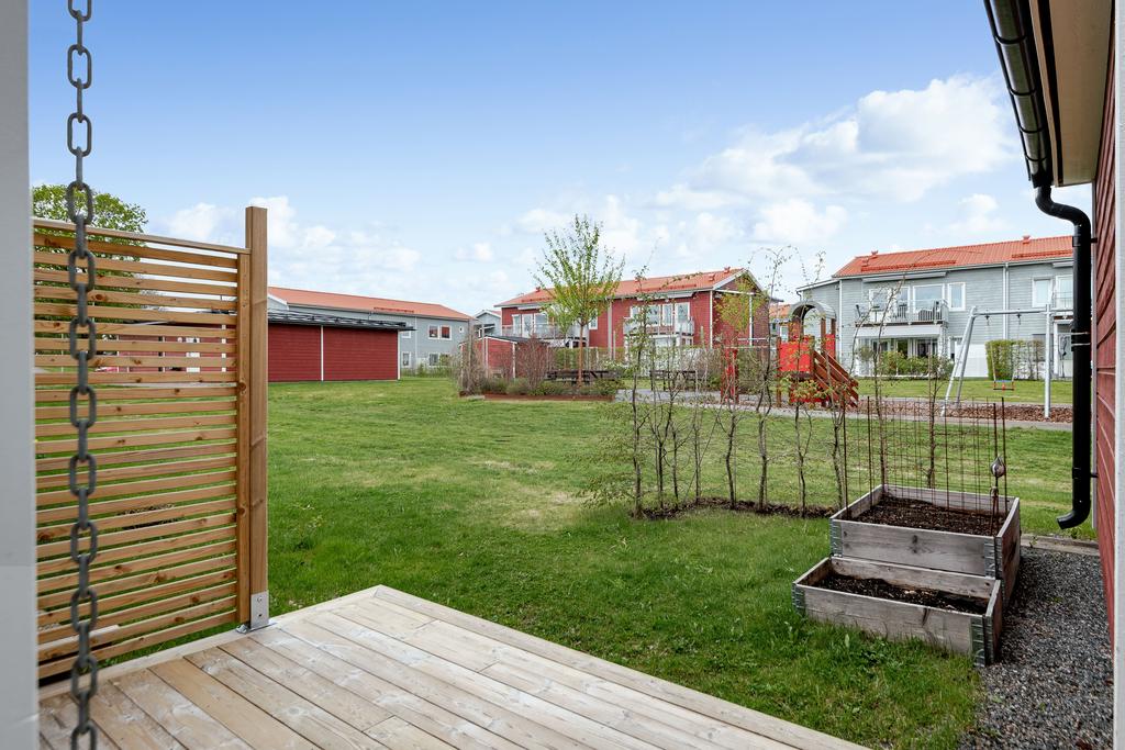Baksida med altan, gräs, pallkragar,  och den gemensamma ytan med lekparken. Allt i bästa kvällssolsläge!