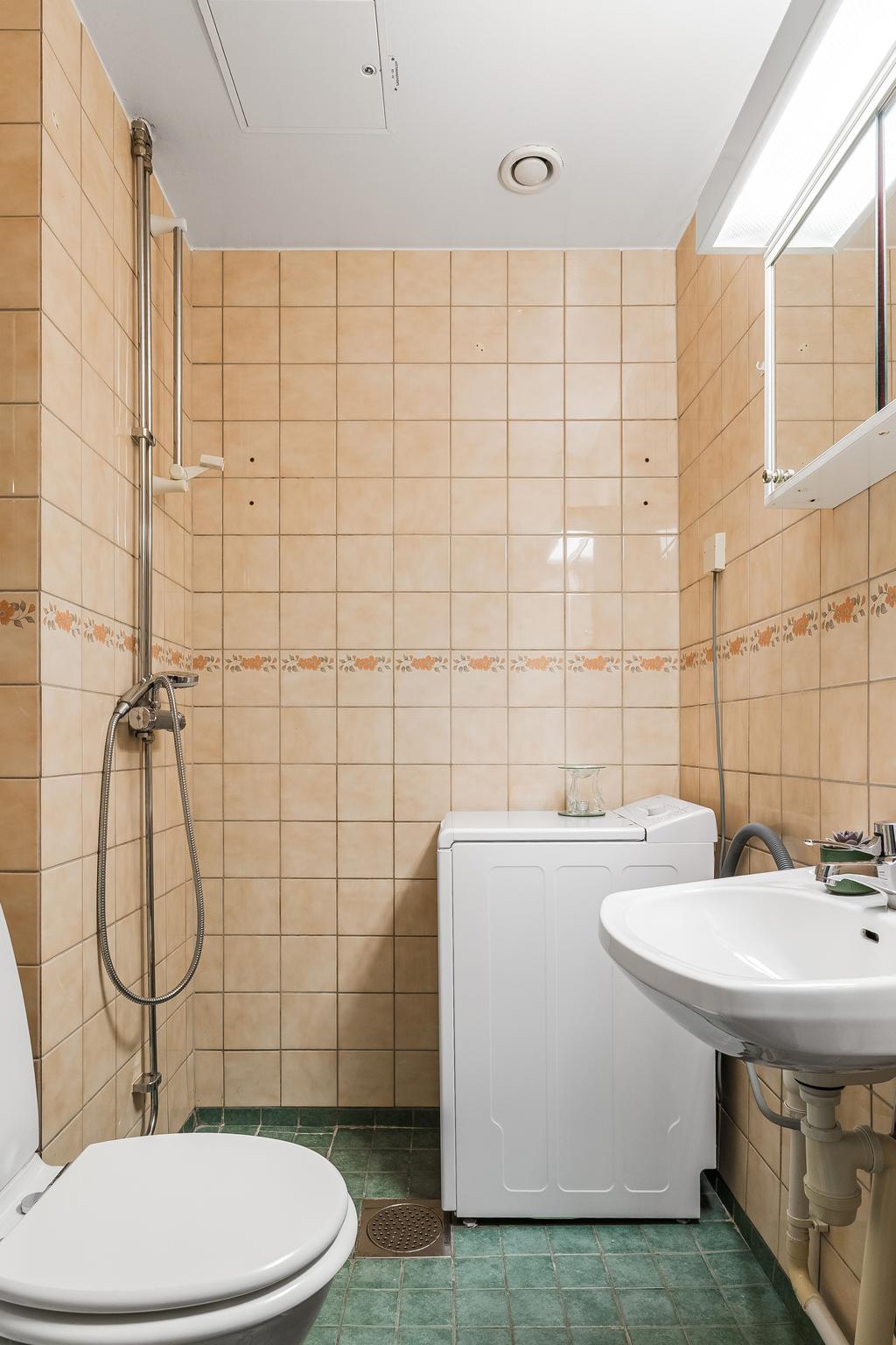 Duschrum med klinkergolv, kaklade väggar och tvättmaskin.
