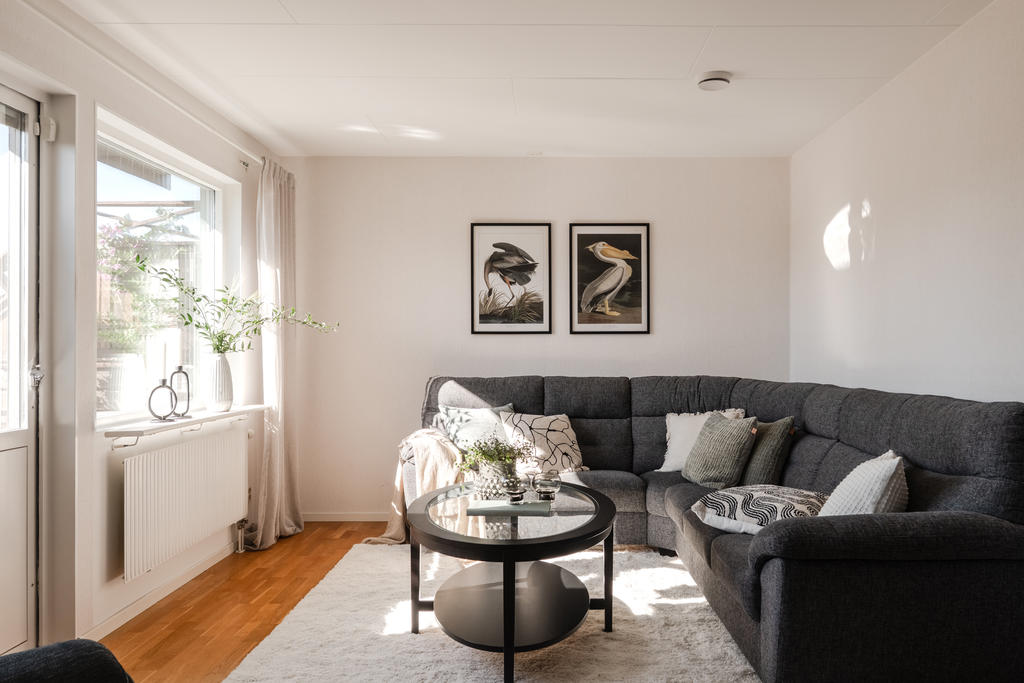 Detta ljusa och inbjudande vardagsrum erbjuder en harmonisk kombination av komfort och stil, med direkt utgång till en solig balkong som förlänger bostadens sociala ytor.
