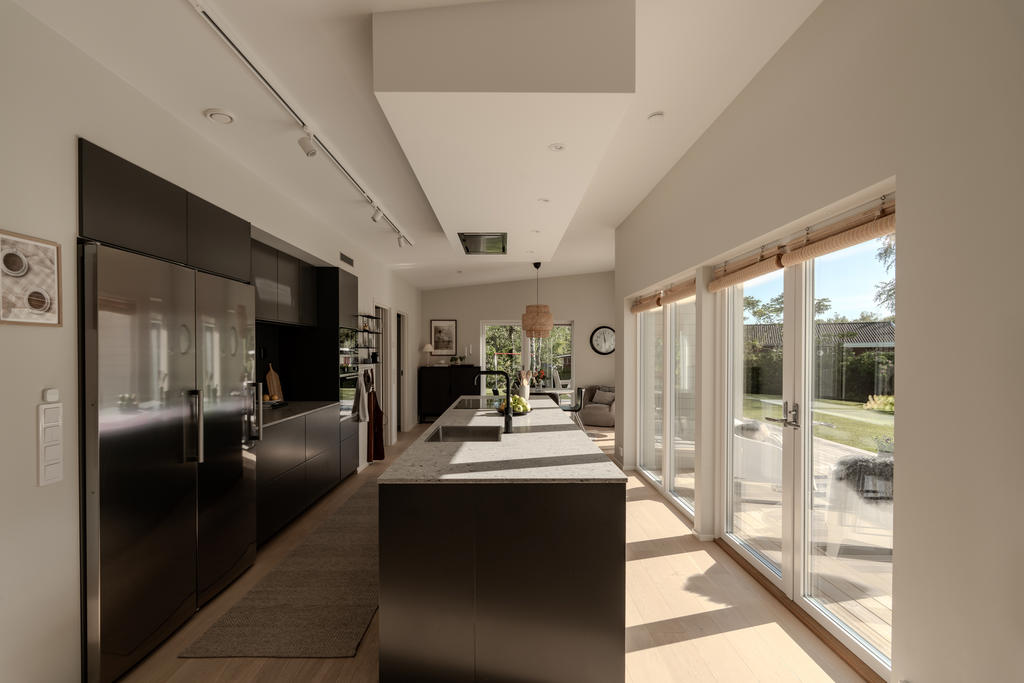 En öppen planlösning i modern stil med stora fönster skapar en ljus, social och funktionell miljö som främjar samvaro och flexibilitet. Denna designfilosofi kombinerar estetik med praktiska lösningar för att maximera utrymme och ljusinsläpp.