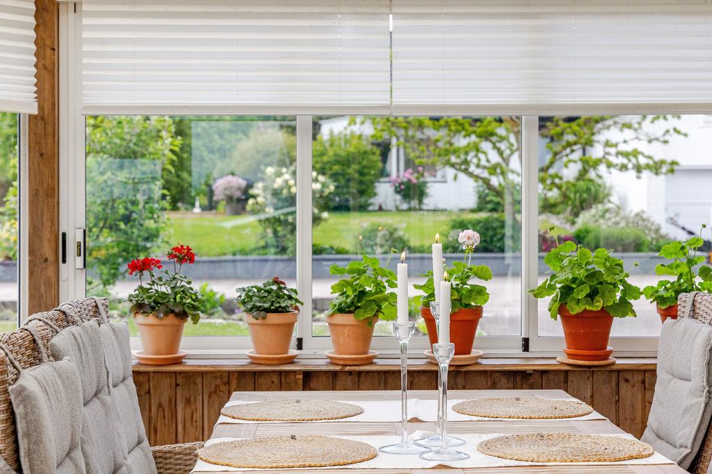 Stort och generöst fönsterparti med utsikt över den grönskande trädgården och en blomstrande fönsterbräda. En idealisk plats för samvaro och avkoppling