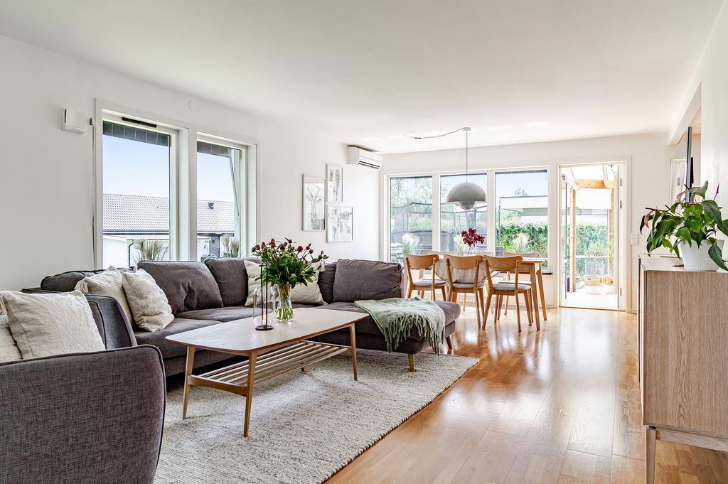 De stora fönsterpartierna och den direkta utgången till det trivsamma uterummet släpper in rikligt med naturligt ljus i vardagsrummet