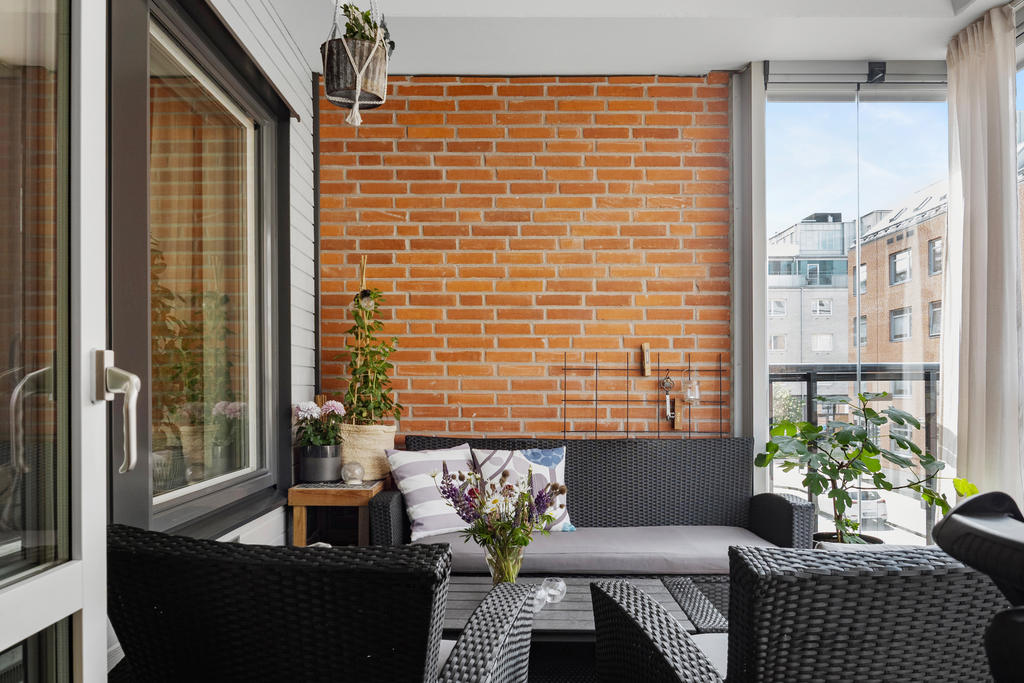 Inglasad balkong med plats för sittgrupp, elgrill och lite växtodling för den med gröna fingrar.