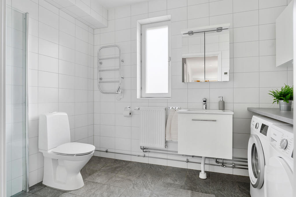 Snyggt helkaklat badrum med tvättmaskin och torktumlare