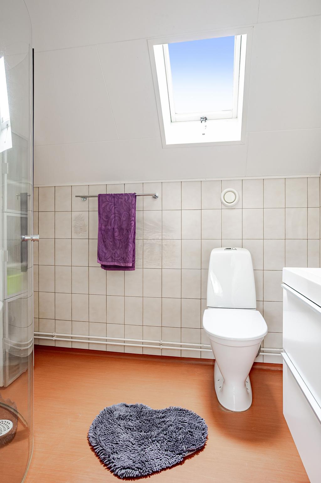 Badrummet på ovanvåningen är delvis kaklar och har ett takfönster som skapar ett naturligt ljusinsläpp 