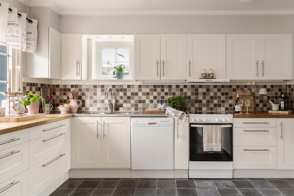 Vit köksinredning med delvis bänkskiva i trä som fint bryter av