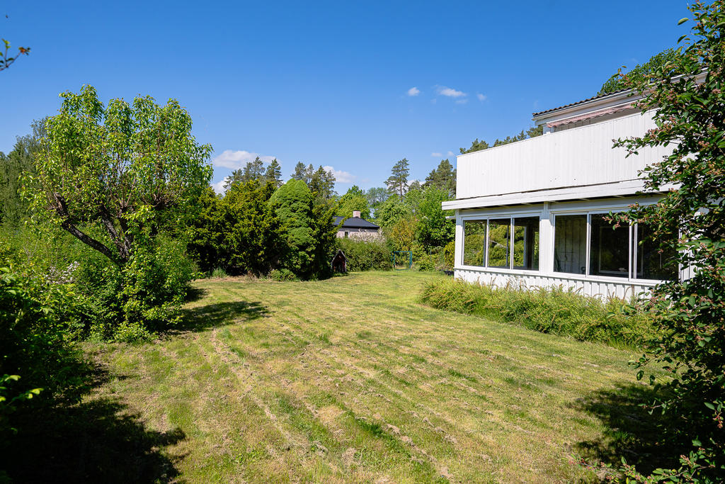 Trädgårdens baksida med inglasad altan