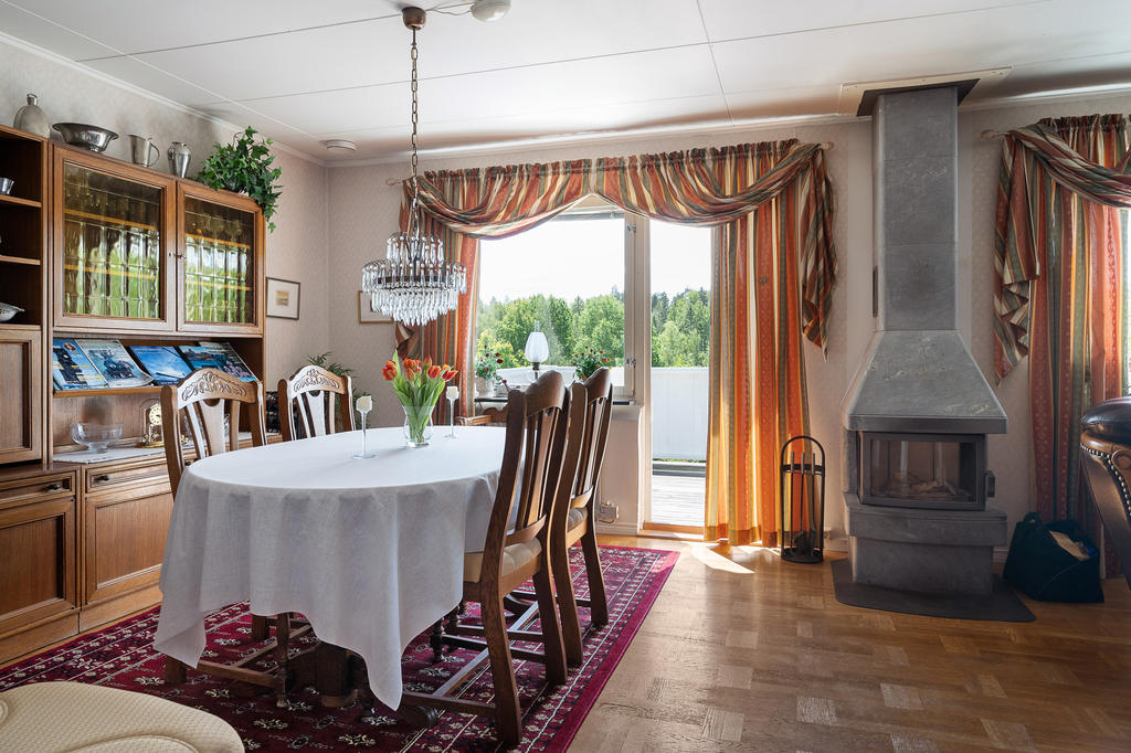 Vardagsrum med matplats, täljstenskamin och utgång till balkong