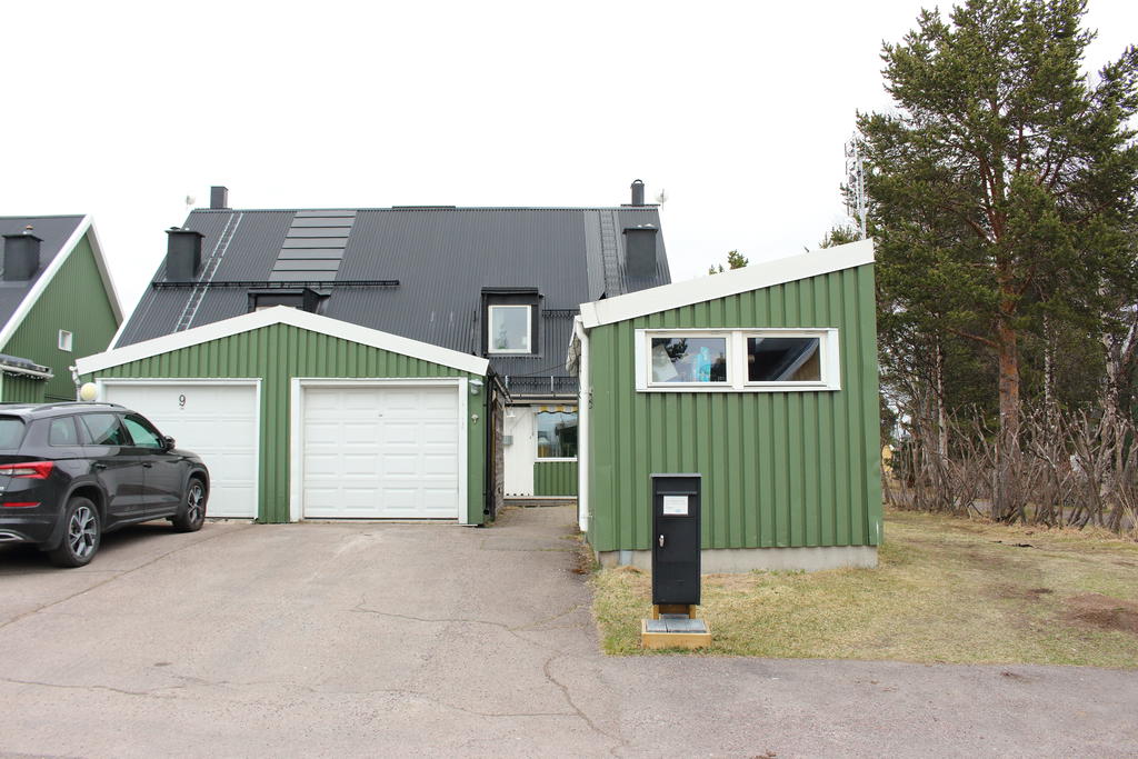 Garage med motordriven port och förråd framför huset