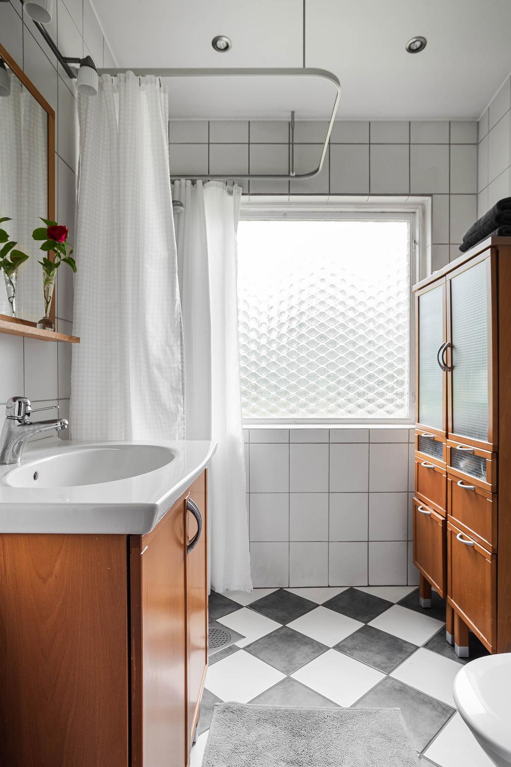 Stilrent badrum som renoverades 2002 med klassiska materialval i form av vitt kakel och schackrutigt klinkergolv.