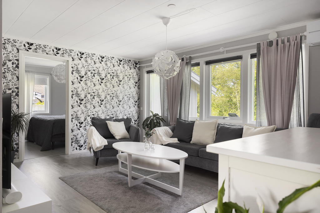 Vardagsrum med stora fina fönter och dörrparti mot altan